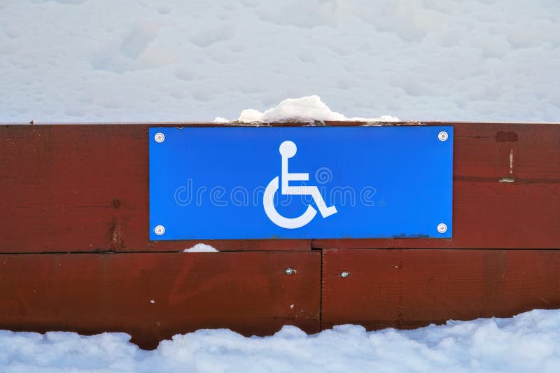 Disabled Parking sign on a low wooden fence in winter, close up. Disabled Parking sign on a low wooden fence in winter, close up