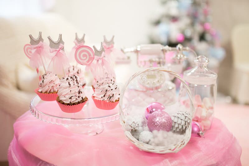 Cartão de Natal, tabela cor-de-rosa doce com cones dos bolos, em um fundo da árvore de Natal foto de stock Cartão de Natal, tabela cor-de-rosa doce com cones dos bolos, em um fundo da árvore de Natal foto de stock