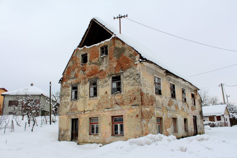 Casa abbandonata con le finestre rotte ed i mattoni caduti coperti in neve immagini stock Casa abbandonata con le finestre rotte ed i mattoni caduti coperti in neve immagini stock