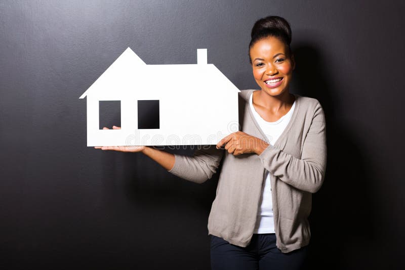 Happy african american woman showing house symbol over black background. Happy african american woman showing house symbol over black background