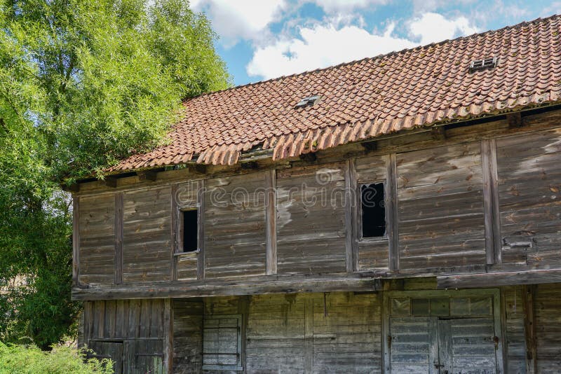 Casa de madeira abandonada velha com um telhado de desintegração da argila foto de stock Casa de madeira abandonada velha com um telhado de desintegração da argila foto de stock