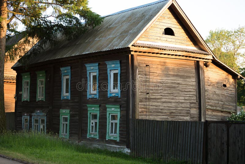 Casa de madeira velha da dois-loja na cidade provincial do russo no por do sol