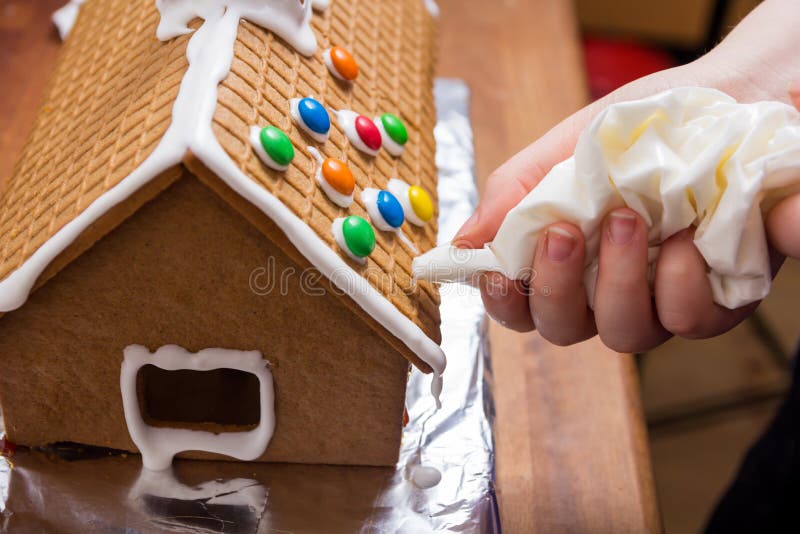 Decorating a gingerbread house with glacing from a syringe. Decorating a gingerbread house with glacing from a syringe