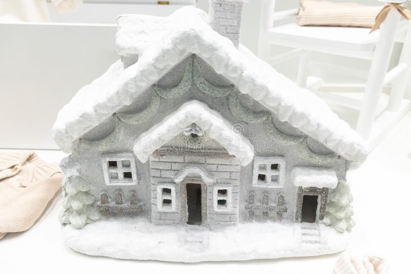 Casa decorativa del invierno plástico gris con el tejado nevoso en el frente de la tienda imágenes de archivo libres de regalías Casa decorativa del invierno plástico gris con el tejado nevoso en el frente de la tienda imágenes de archivo libres de regalías