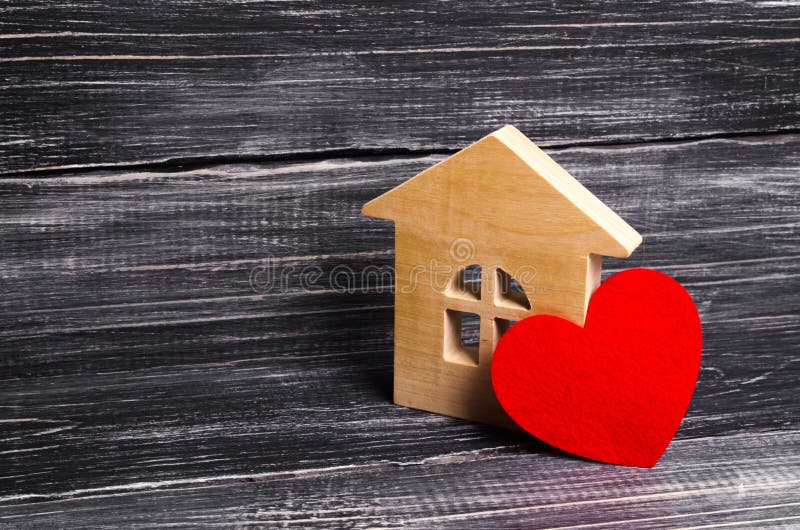 Casa di legno con un cuore rosso su un fondo di legno scuro Una casa per gli amanti, una luna di miele Acquisti il vostro proprio