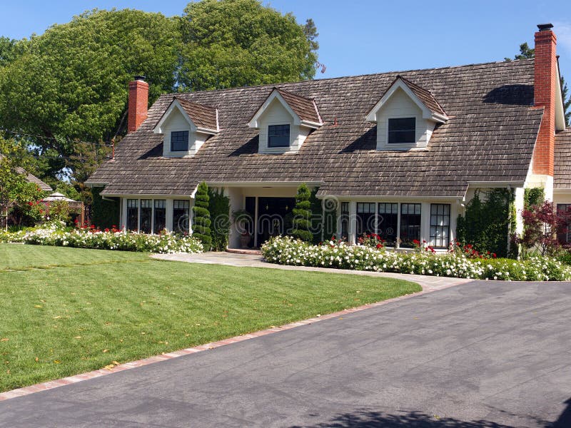 Luxury house with large frontyard and three attic windows. Large wooden shingle roof and two red chimneys. Luxury house with large frontyard and three attic windows. Large wooden shingle roof and two red chimneys