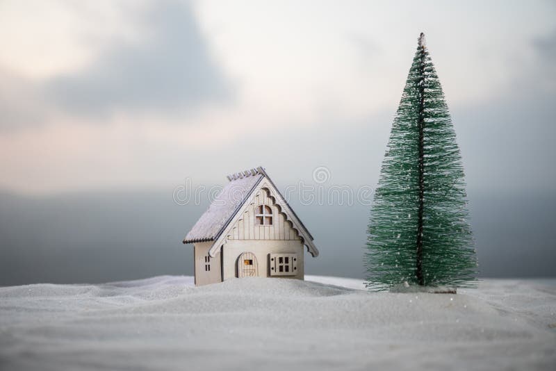 Casa diminuta do Natal e do ano novo na neve na luz solar Pouco casa do brinquedo na neve com árvore Fundo festivo foto de stock Casa diminuta do Natal e do ano novo na neve na luz solar Pouco casa do brinquedo na neve com árvore Fundo festivo foto de stock