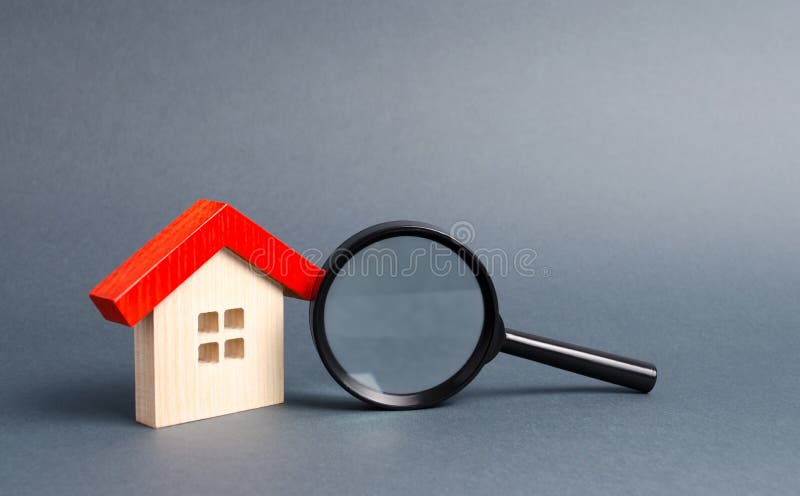 Casa e lente d'ingrandimento di legno su un fondo grigio Comprando e vendendo bene immobile, le costruzioni nuove di costruzione, fotografie stock Casa e lente d'ingrandimento di legno su un fondo grigio Comprando e vendendo bene immobile, le costruzioni nuove di costruzione, fotografie stock