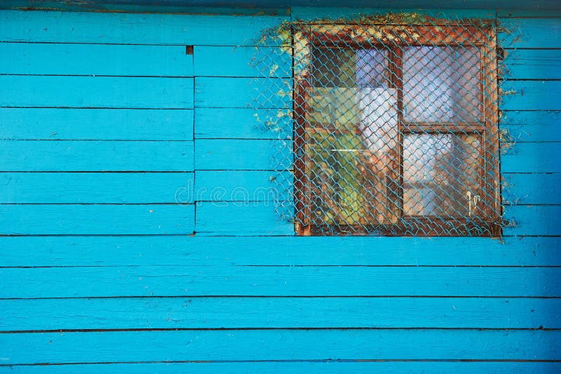 Casa ou celeiro azul de madeira velho com uma janela pequena barrada foto de stock Casa ou celeiro azul de madeira velho com uma janela pequena barrada foto de stock