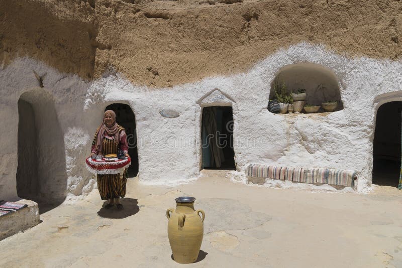 Underground House of trogladites in the desert of Tunisia,Matmata. Africa. Local woman serving the tea. Underground House of trogladites in the desert of Tunisia,Matmata. Africa. Local woman serving the tea.