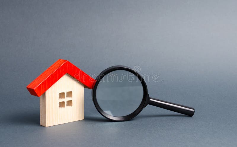 Wooden house and magnifying glass on a gray background. Buying and selling real estate, building new buildings, offices and homes. House search. The concept of urban planning, infrastructure projects. Wooden house and magnifying glass on a gray background. Buying and selling real estate, building new buildings, offices and homes. House search. The concept of urban planning, infrastructure projects