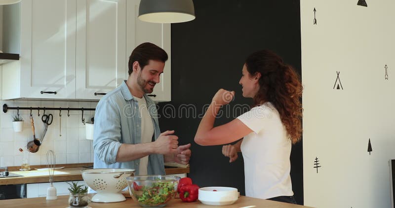 Casal caucasiano amoroso e alegre dançando na cozinha.