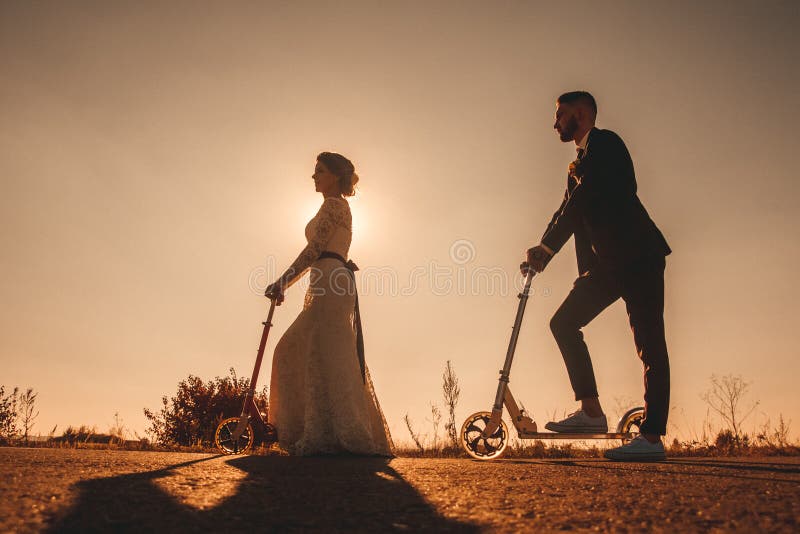 Casal de silhuetas cavalgando uma moto ao longo da estrada fora da cidade ao pôr do sol foto de stock royalty free Casal de silhuetas cavalgando uma moto ao longo da estrada fora da cidade ao pôr do sol foto de stock royalty free