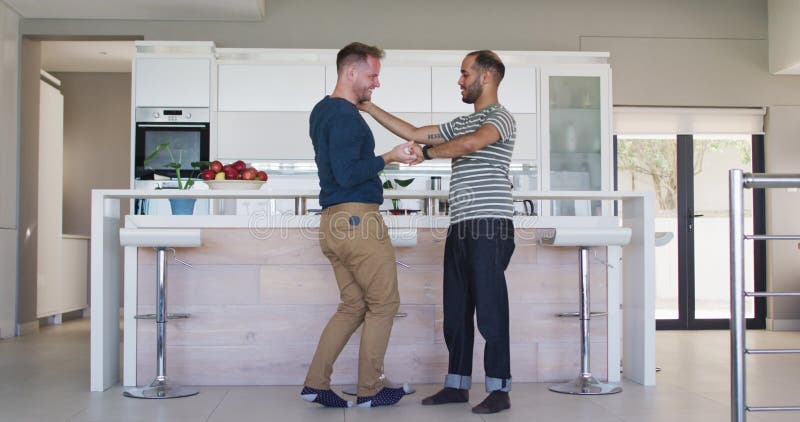 Casal gay multiétnico dançando na cozinha