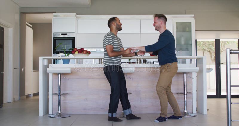 Casal gay multiétnico dançando na cozinha