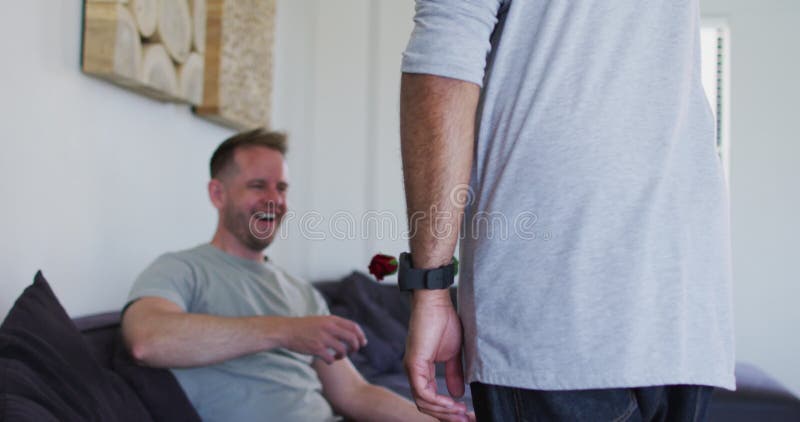 Casal gay multiétnico sorrindo um dando rosa vermelha