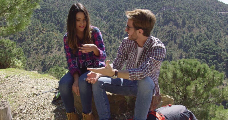 Casal jovem descansando em pedra nas montanhas