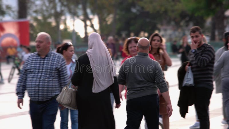 Casal muçulmano se reunindo usando smartphone em pé na rua de uma cidade lotada.