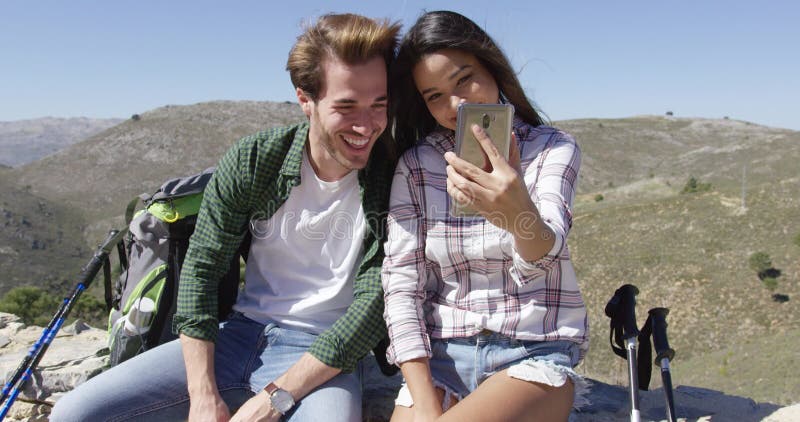 Casal sorridente tomando selfie em montanhas