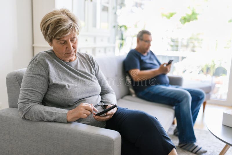 Casal sênior usando seus celulares em casa imagens de stock royalty free