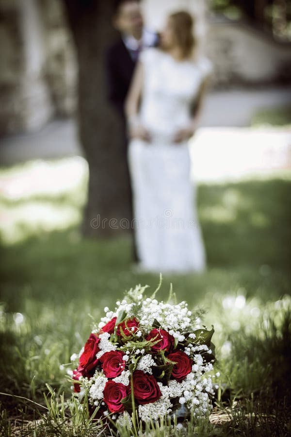Casandose las flores en el primero plano y novia y novio borrosos en fondo imágenes de archivo libres de regalías Casandose las flores en el primero plano y novia y novio borrosos en fondo imágenes de archivo libres de regalías