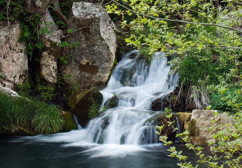 Image shows a small waterfall in a European forest. Image shows a small waterfall in a European forest