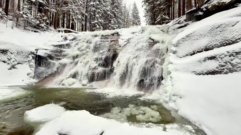 Cascada de agua congelada y bosque de nieve de invierno. Vista de zoom almacen de video