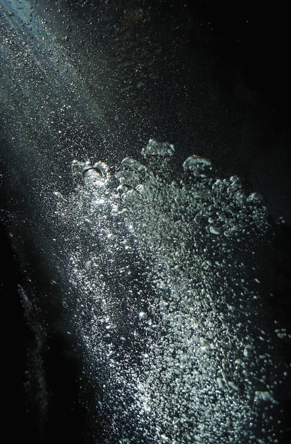 En cascada ascendiendo desgarrando de burbujas crecimiento k eje de la luz en oscuro negro burbujas transmisión arriba sobre el superficie k la luz.