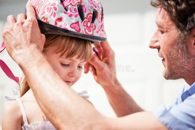 Casco da bicicletta e figlio con supporto di padre per la protezione e l'insegnamento durante il fine settimana. amore familiare e immagini stock libere da diritti
