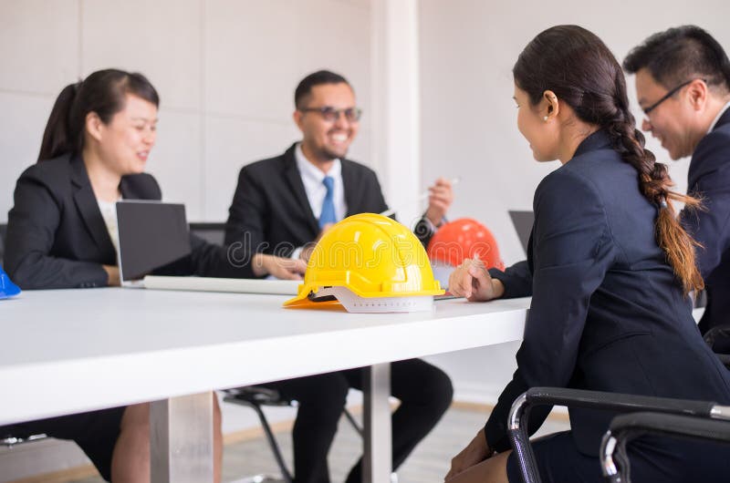 Casco di sicurezza dei caschi nella sala riunioni, Blured dell'architetto della gente e dell'ingegnere all'ufficio fotografia stock libera da diritti Casco di sicurezza dei caschi nella sala riunioni, Blured dell'architetto della gente e dell'ingegnere all'ufficio fotografia stock libera da diritti