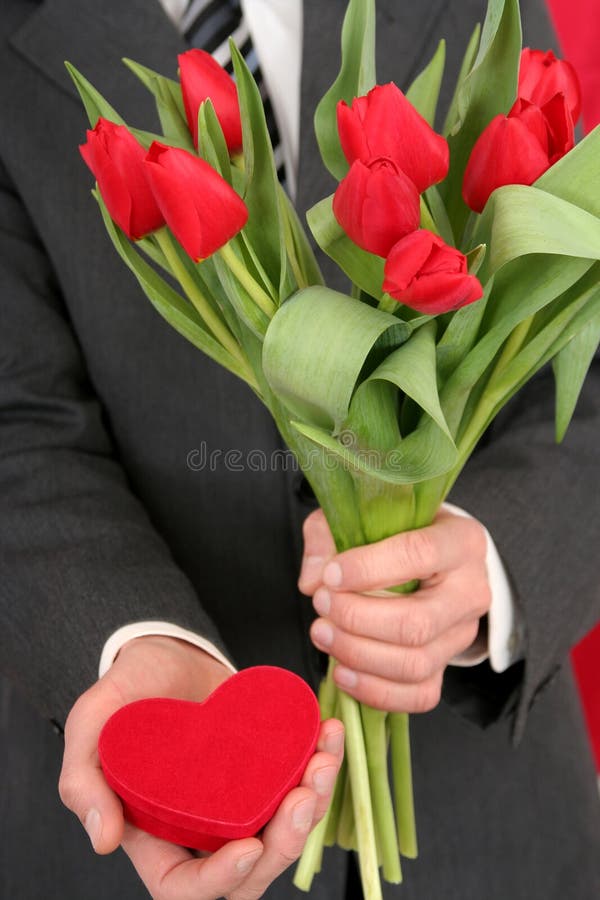 Casella e fiori a forma di cuore della holding dell'uomo immagine stock libera da diritti Casella e fiori a forma di cuore della holding dell'uomo immagine stock libera da diritti