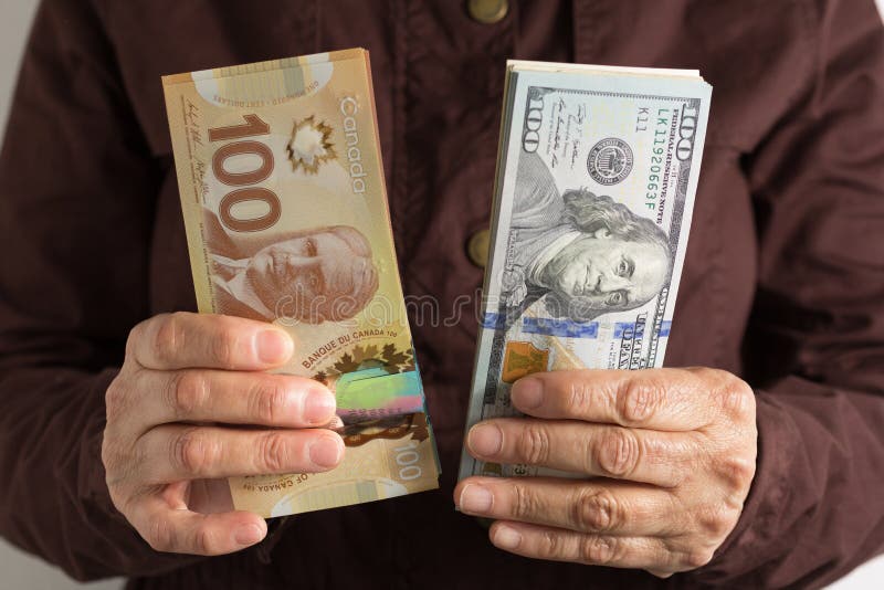 Cash bills from Canada and USA currency. Front view senior person holding bills.