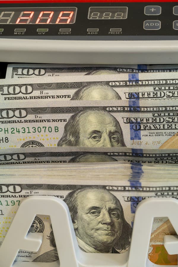 Cash counting machine displaying stacked hundred dollar bills in use royalty free stock photography