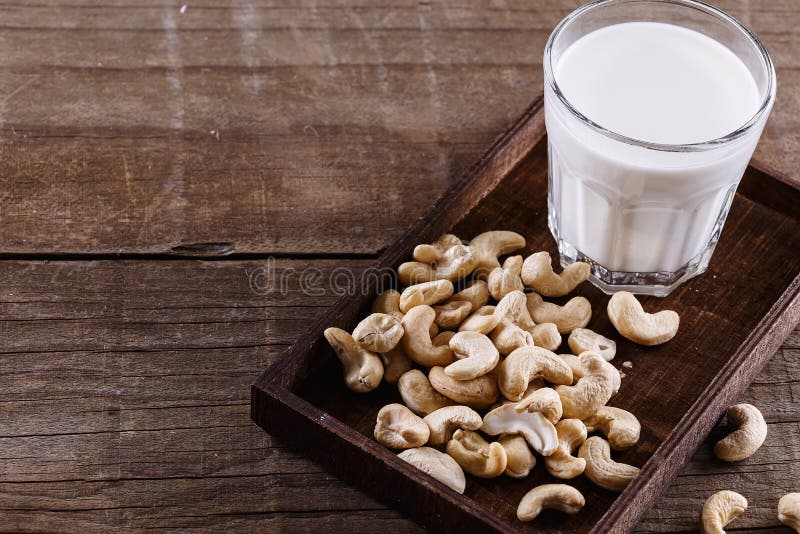 Cashew milk over rustic wooden background. Glass of cashew milk and nuts over rustic wooden background stock image