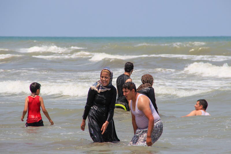 Caspian Sea, Iran - May 25, 2017: people have fun and swim dressed in the sea for the weekend. Muslim swim in clothes and shawls