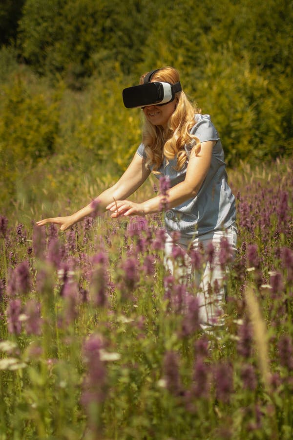 Casque weating de réalité virtuelle de femme se reposant au milieu d'un champ des fleurs Expérience d'Immersive VR photo libre de droits Casque weating de réalité virtuelle de femme se reposant au milieu d'un champ des fleurs Expérience d'Immersive VR photo libre de droits