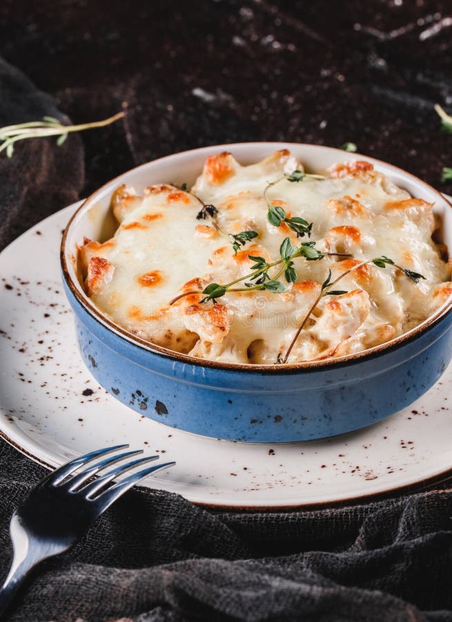 Casserole with cheese, broccoli, cauliflower and herbs in bowl over dark background with napkin. Healthy dinner or lunch setting, stock photo Casserole with cheese, broccoli, cauliflower and herbs in bowl over dark background with napkin. Healthy dinner or lunch setting, stock photo