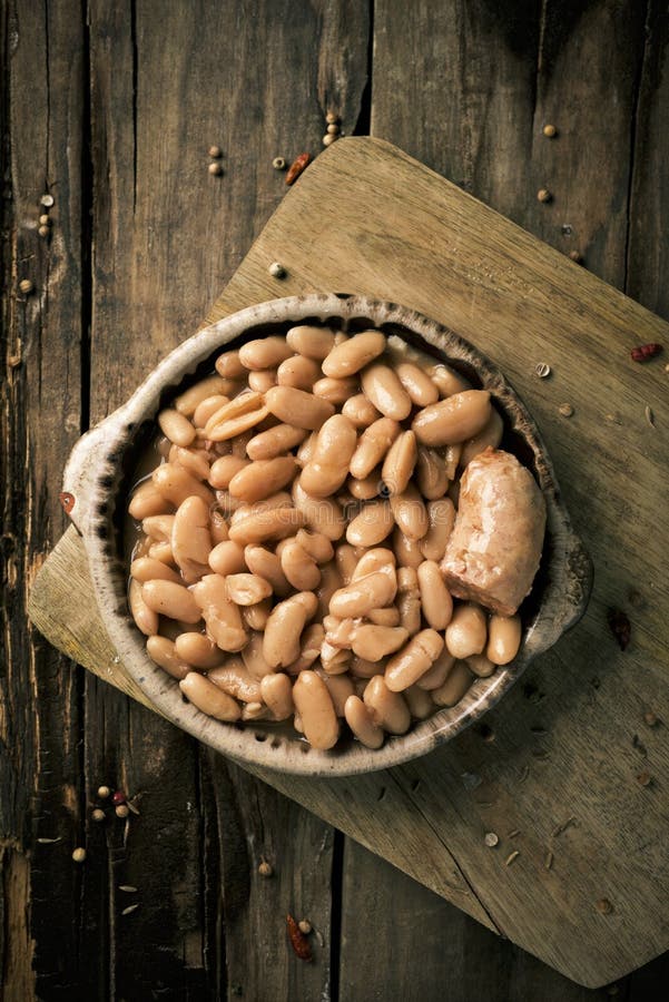 High-angle shot of an earthenware bowl with a cassoulet de Castelnaudary, a typical bean stew from Occitanie, in France, on a rustic wooden table. High-angle shot of an earthenware bowl with a cassoulet de Castelnaudary, a typical bean stew from Occitanie, in France, on a rustic wooden table