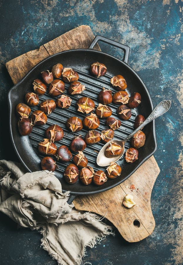Castagne arrostite nel grigliare pentola sopra fondo blu scuro immagini stock Castagne arrostite nel grigliare pentola sopra fondo blu scuro immagini stock