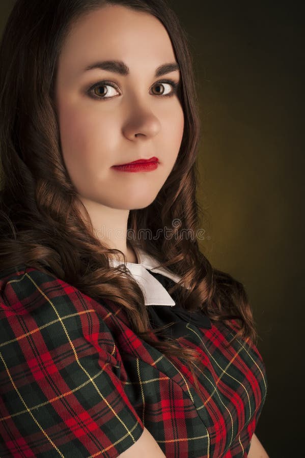 Castana sveglio in vestito dal tartan con le labbra e i curles rossi Ritratto dello studio immagini stock Castana sveglio in vestito dal tartan con le labbra e i curles rossi Ritratto dello studio immagini stock