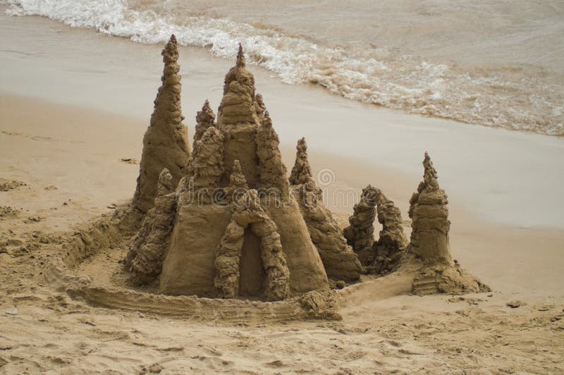 Intricate sand castle by the sea with some waves. Intricate sand castle by the sea with some waves