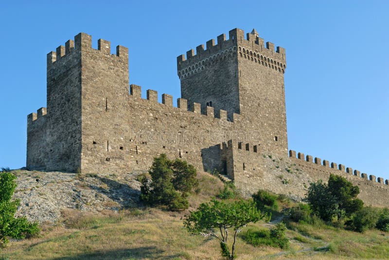 The tower of a Genoese fortress is situated against the blue sky background. This is an old Genoese Sudak Castle, Crimea. The tower of a Genoese fortress is situated against the blue sky background. This is an old Genoese Sudak Castle, Crimea.