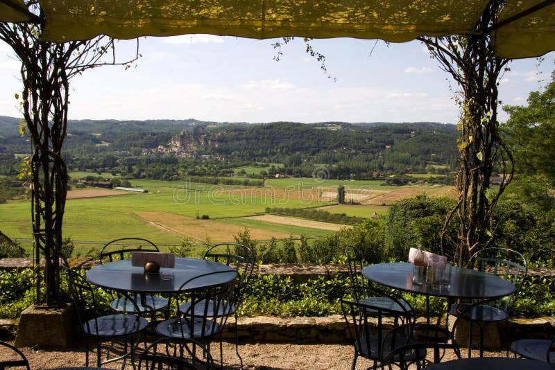View of Beynac Castle in the Dordogne valley, France, from Marqueyssac Gardens, with cafe tables and chairs set out on the terrace in the foreground. View of Beynac Castle in the Dordogne valley, France, from Marqueyssac Gardens, with cafe tables and chairs set out on the terrace in the foreground
