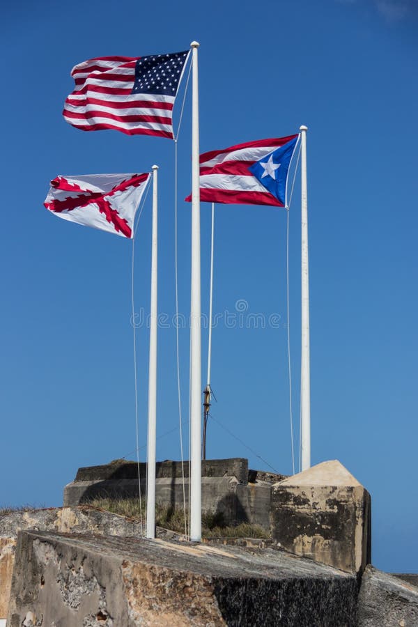 CASTILLO DE SAN FELIPE DEL MORRO, PORTO RICO, EUA - 16 DE FEVEREIRO DE 2015: Três bandeiras do Estados Unidos, do Porto Rico e da foto de stock CASTILLO DE SAN FELIPE DEL MORRO, PORTO RICO, EUA - 16 DE FEVEREIRO DE 2015: Três bandeiras do Estados Unidos, do Porto Rico e da foto de stock