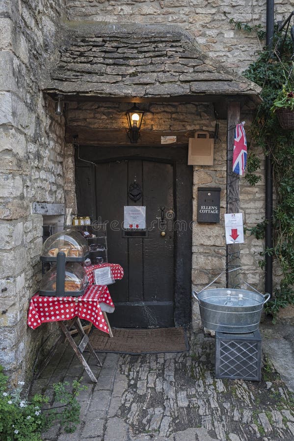 Beautiful front of old stone cottage with set up table selling home made cakes in the picturesque Castle Combe Village, Chippenham