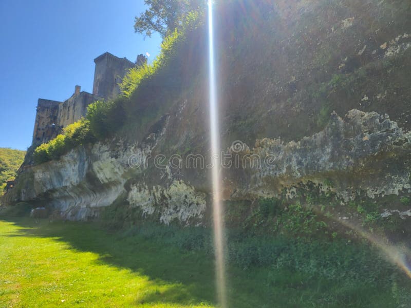 Castle Ruins on a Sunlit Cliffside with Vibrant Greenery stock photography
