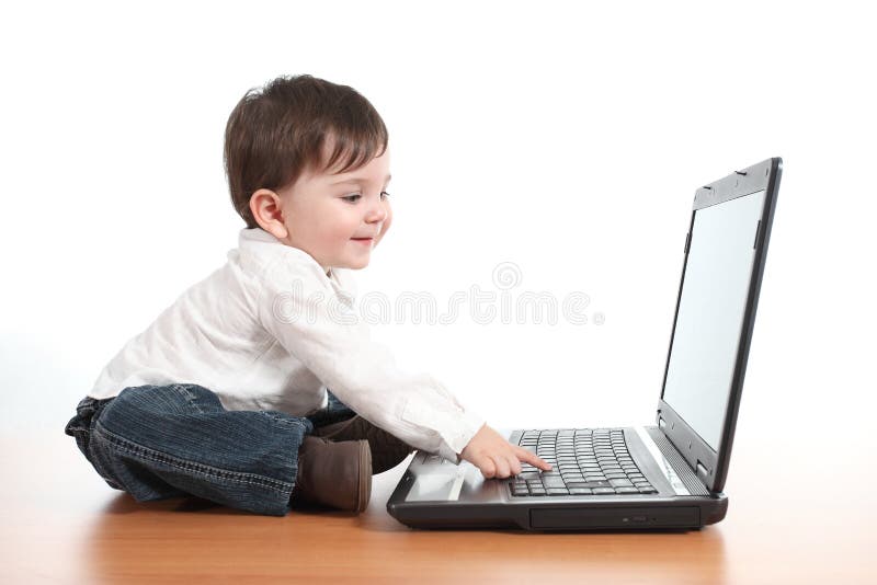 Casual baby smiling while is playing with a laptop computer stock photography