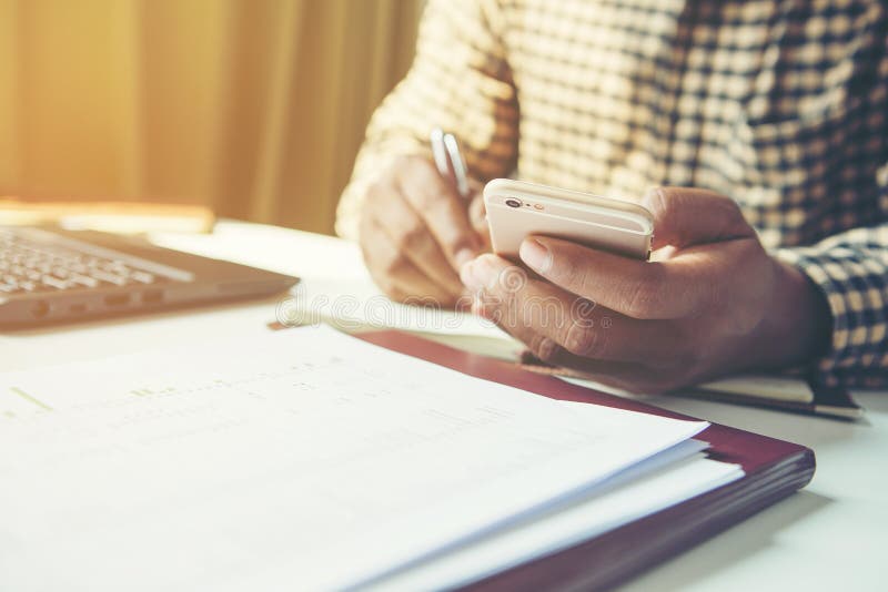 Casual business man using mobile smart phone working, taking note, schedule on paper notebook, reading e book application. E stock photography