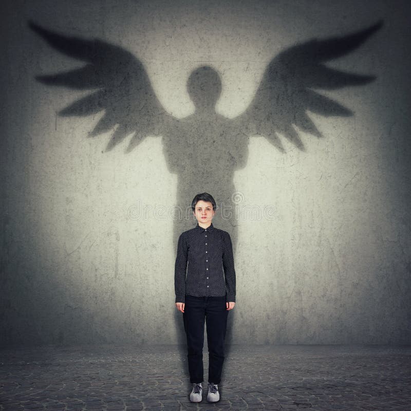 Casual confident woman full length portrait casting a superhero shadow with angel wings on a dark room wall. Super power, inner stock image Casual confident woman full length portrait casting a superhero shadow with angel wings on a dark room wall. Super power, inner stock image