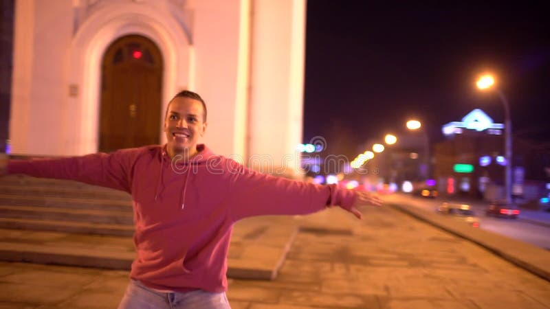 Casual portrait of happy smiling Latino male in stylish hat dancing on city street. Young attractive Hispanic man on his stock footage